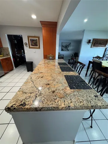 a large kitchen with kitchen island granite countertop a refrigerator stove microwave and sink
