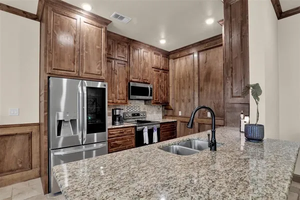 a kitchen with stainless steel appliances granite countertop a refrigerator a stove a sink and a granite counter tops