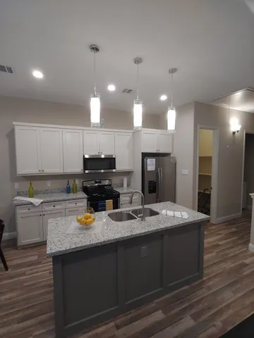 a kitchen with a sink dishwasher a stove and a refrigerator with wooden floor