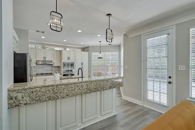 a kitchen with stainless steel appliances kitchen island granite countertop a sink refrigerator and cabinets