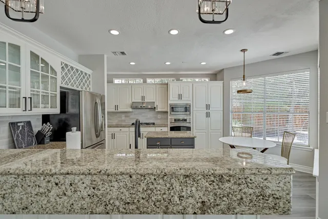 a kitchen with kitchen island white cabinets and stainless steel appliances