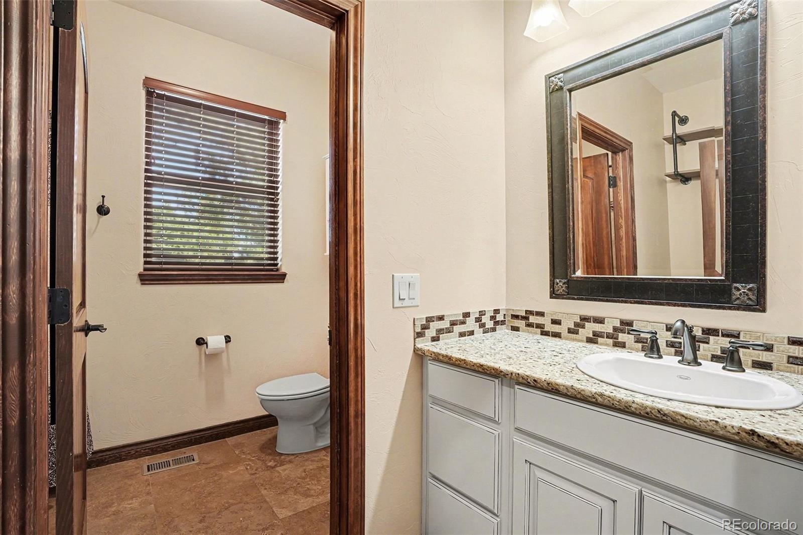 7936 Monarch Road Larkspur, CO 80118 - Photo 16 of 24 a bathroom with a granite countertop sink toilet and mirror