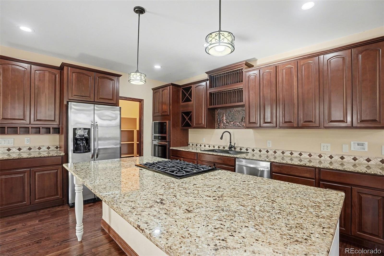 7936 Monarch Road Larkspur, CO 80118 - Photo 6 of 24 a kitchen with stainless steel appliances kitchen island granite countertop a stove refrigerator and cabinets
