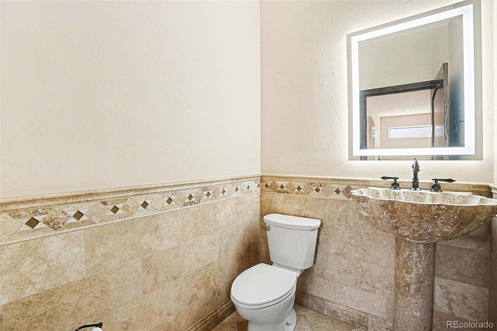 7936 Monarch Road Larkspur, CO 80118 - Photo 7 of 24 a bathroom with a granite countertop sink a toilet and a mirror