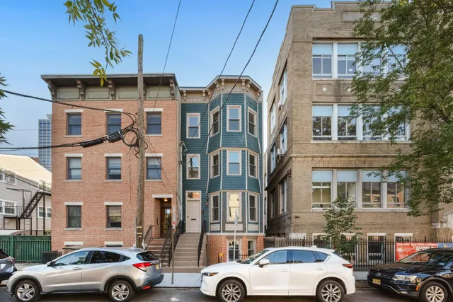 a front view of a building with cars parked
