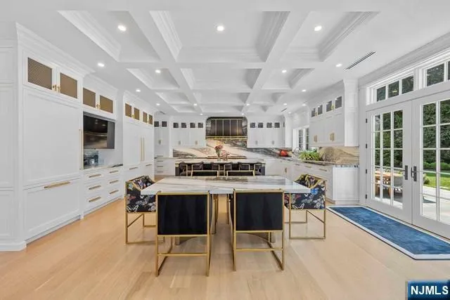 a kitchen with stainless steel appliances granite countertop a stove top oven a sink a dining table and chairs