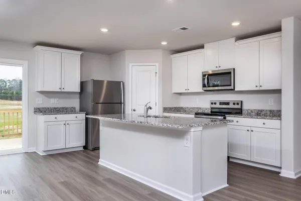 a kitchen with granite countertop a refrigerator stove top oven and sink