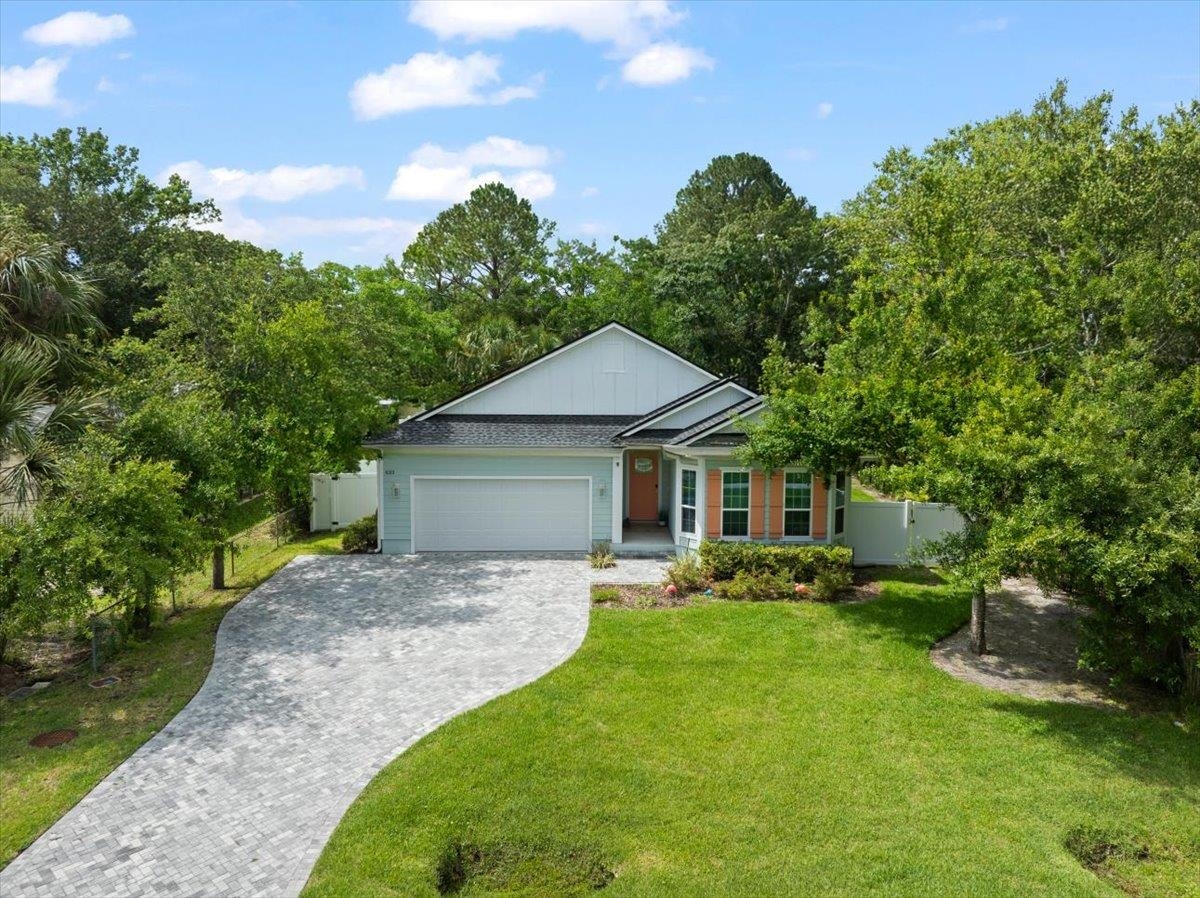 a view of a house with a big yard plants and large tree