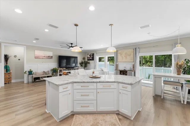 a large kitchen with kitchen island a large counter space a sink appliances and a large window