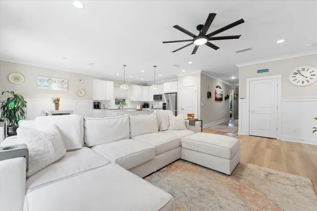 a living room with furniture kitchen view and a chandelier