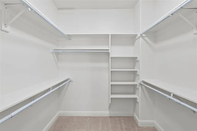 a view of an empty room with wooden floor and a ceiling fan