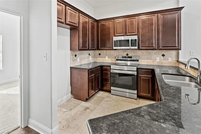 a kitchen with stainless steel appliances granite countertop a stove a sink and a microwave