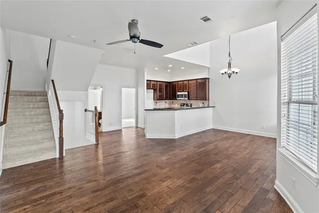 a view of a kitchen with kitchen island a sink wooden floor and stainless steel appliances