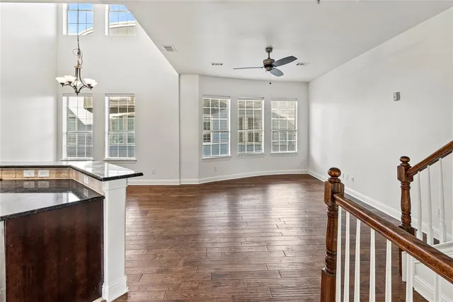 a view of a kitchen and an empty room with wooden floor