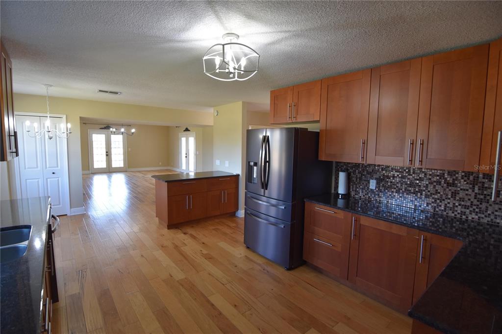 3233 Hickory Tree Road St. Cloud, FL 34772 - Photo 10 of 23 a kitchen with stainless steel appliances granite countertop wooden floors a stove and a refrigerator