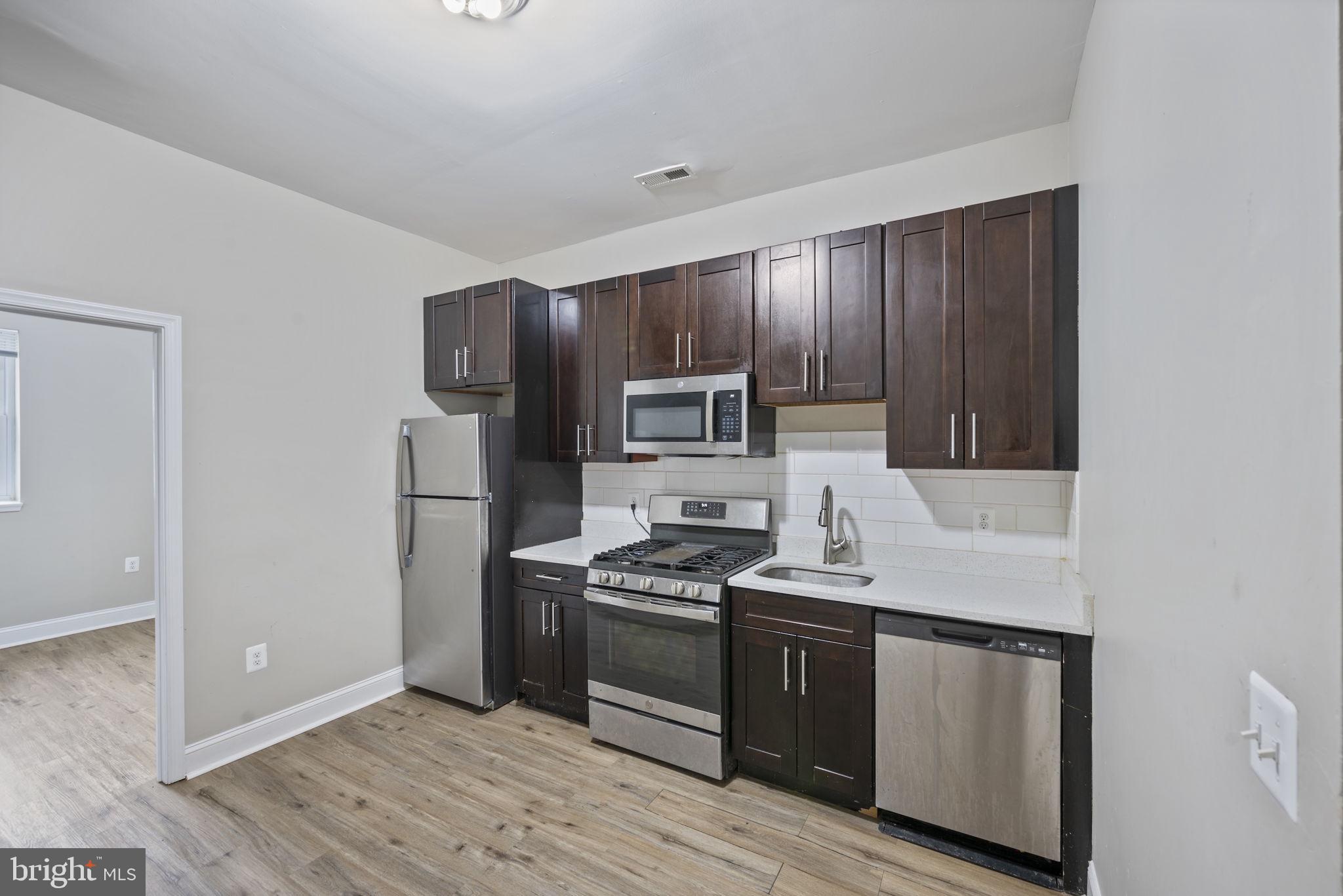 3619 Cottage Avenue Baltimore, MD 21215 - Photo 13 of 31 a kitchen with granite countertop wooden cabinets and stainless steel appliances