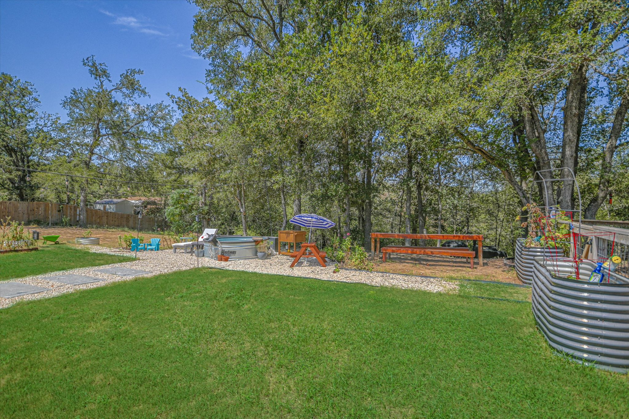 671 Shiloh Road Bastrop, TX 78602 - Photo 19 of 21 Thoughtfully designed outdoor space features mature trees, gravel pathways, raised garden beds, and multiple gathering areas.