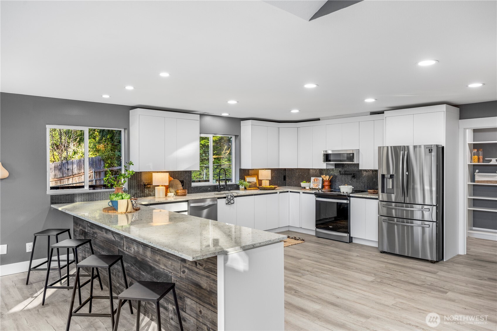 9371 Willamette Meridian Road Northwest Silverdale, WA 98383 - Photo 10 of 40 a kitchen with stainless steel appliances granite countertop a refrigerator a stove top oven a sink dishwasher a dining table and chairs with wooden floor