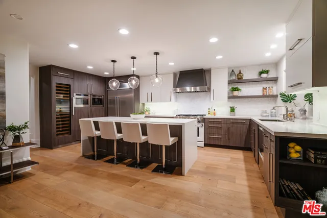 a large kitchen with stainless steel appliances kitchen island granite countertop a stove a sink a refrigerator and a dining table with wooden floor