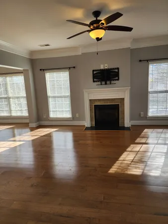 an empty room with wooden floor fireplace and windows