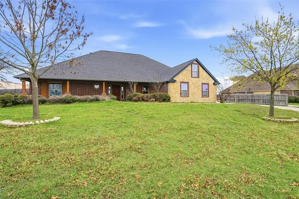 a view of a house next to a big yard and large trees