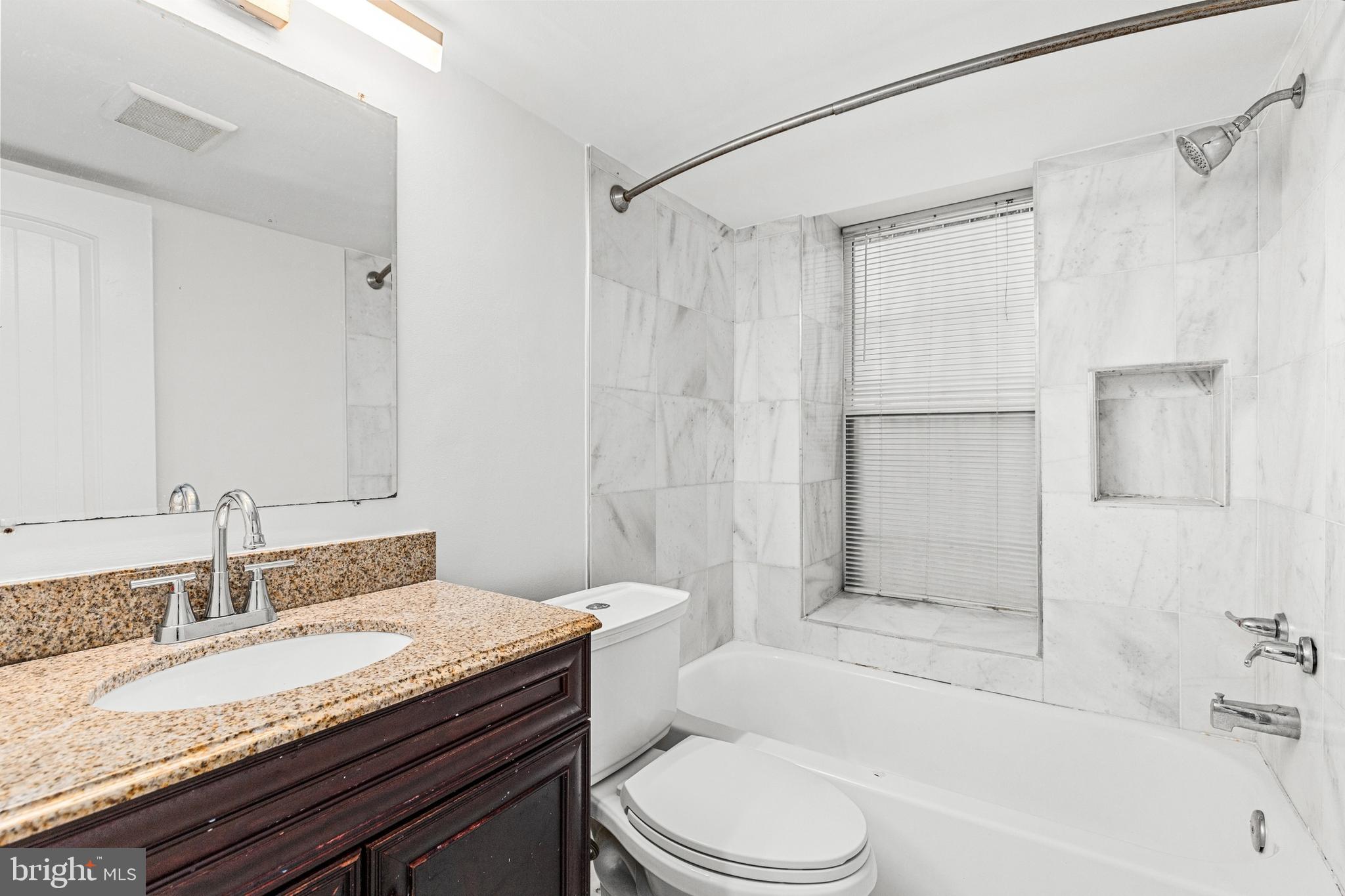 1438 Meridian Place Northwest, Unit LL1 Washington, DC 20010 - Photo 8 of 18 a bathroom with a granite countertop sink toilet a shower and a mirror