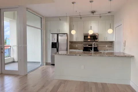 a kitchen with kitchen island a counter top a stove a refrigerator and a cabinets