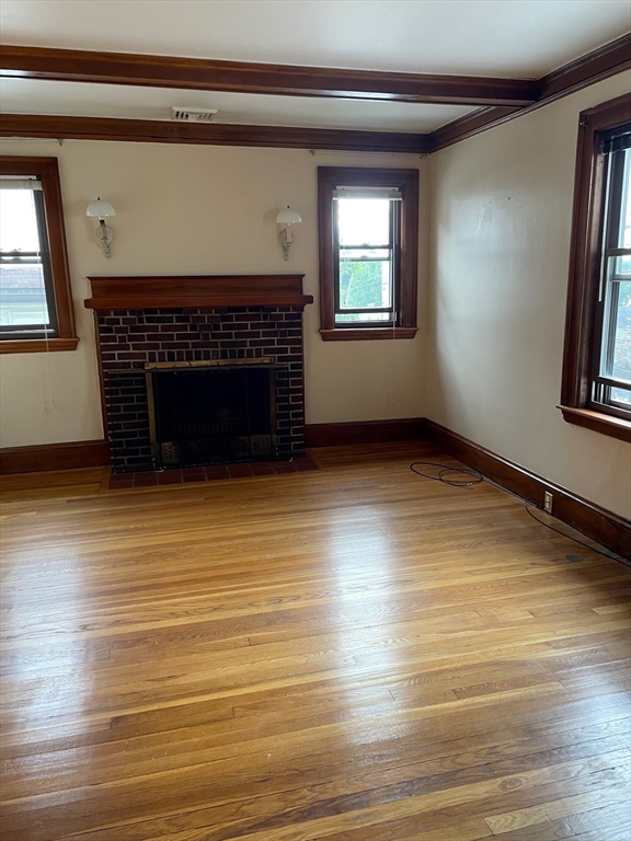 257 Common Street, Unit 2 Watertown, MA 02472 - Photo 11 of 30 an empty room with wooden floor fireplace and windows