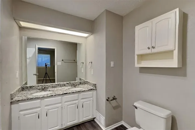 a bathroom with a granite countertop toilet sink and mirror