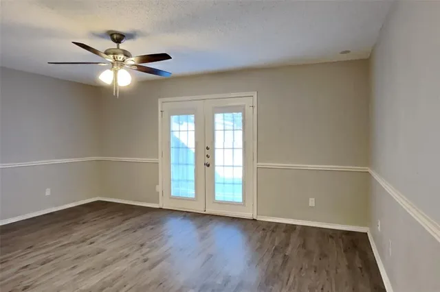 an empty room with wooden floor fan and windows