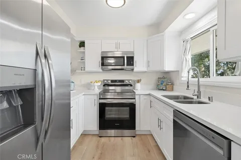 a kitchen with cabinets stainless steel appliances a sink and a window