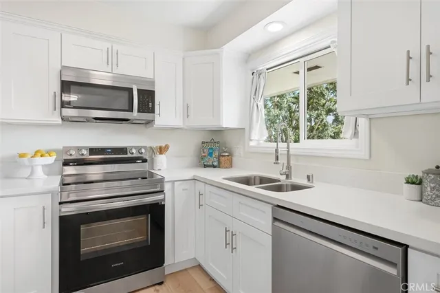 a kitchen with white cabinets appliances and a sink