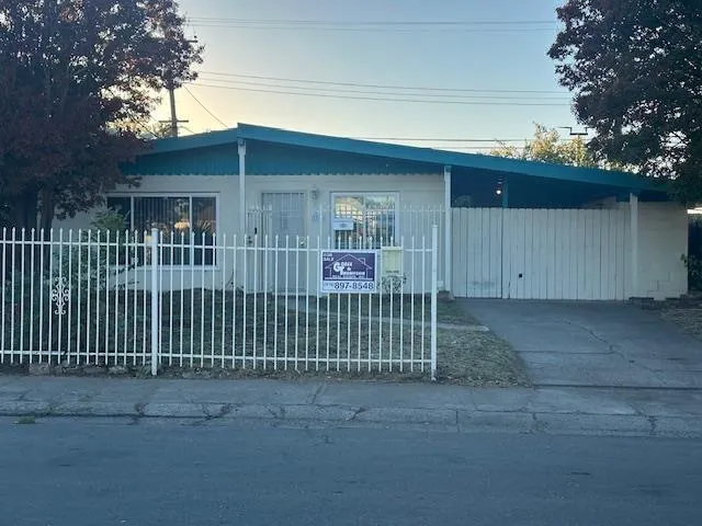a view of a house with a small yard and wooden fence