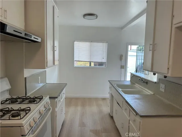 a kitchen with a sink stove top oven and cabinets