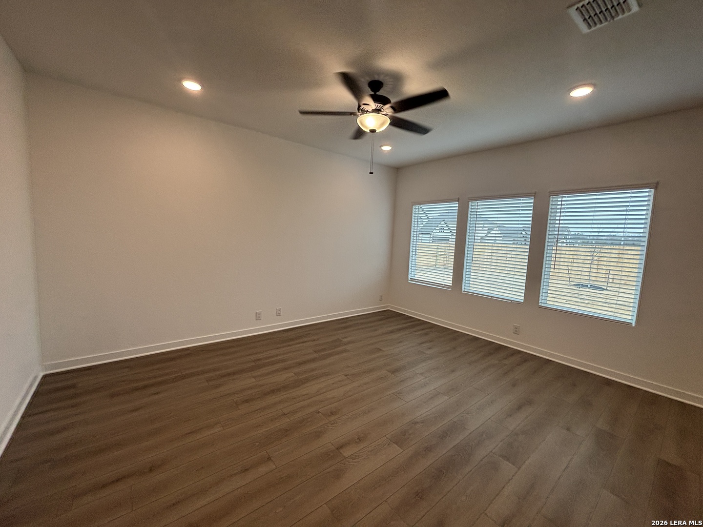 10101 Peppercorn Place Schertz, TX 78154 - Photo 12 of 36 an empty room with wooden floor fan and windows