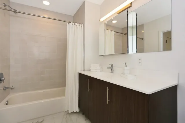a bathroom with a bath tub sink mirror and a shower