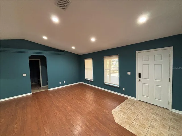 a view of an empty room with window and wooden floor
