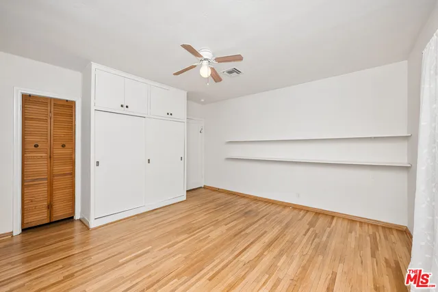 an empty room with wooden floor closet and windows