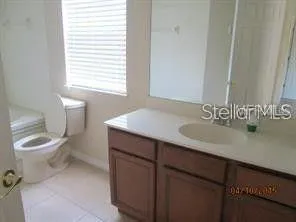 a bathroom with a toilet a sink a mirror and a window