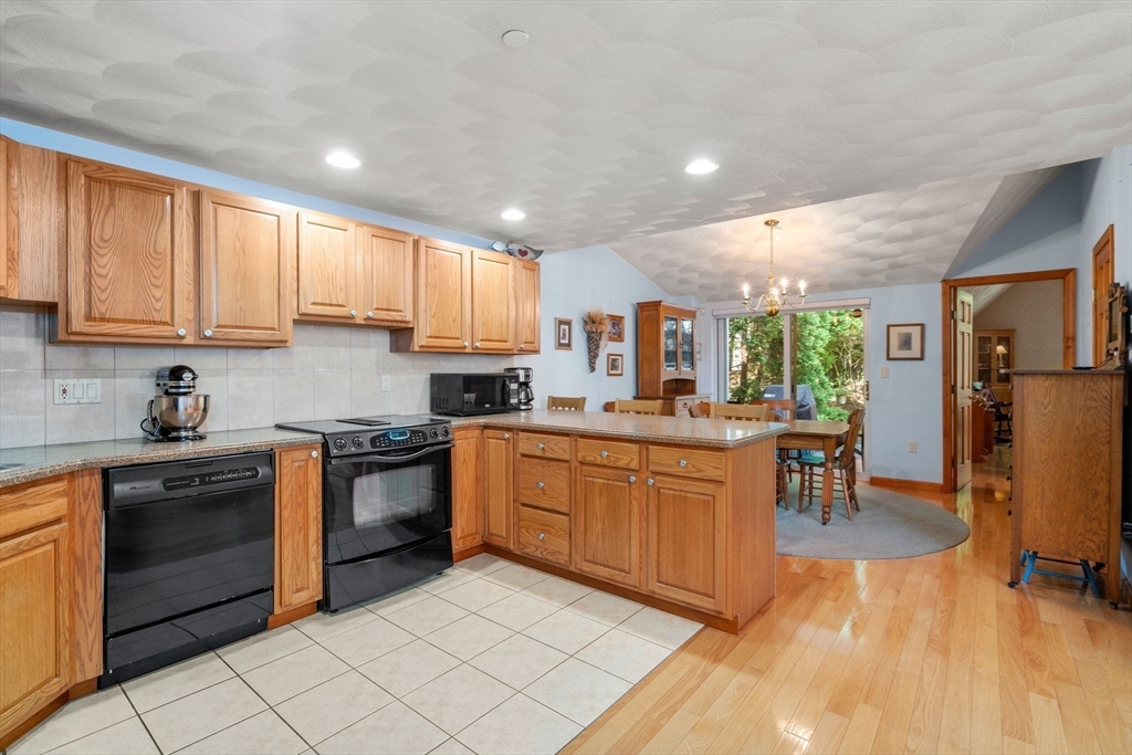 46 Deer Path, Unit 46 Hudson, MA 01749 - Photo 10 of 23 a kitchen with stainless steel appliances granite countertop a stove top oven a sink dishwasher a dining table and chairs with wooden floor