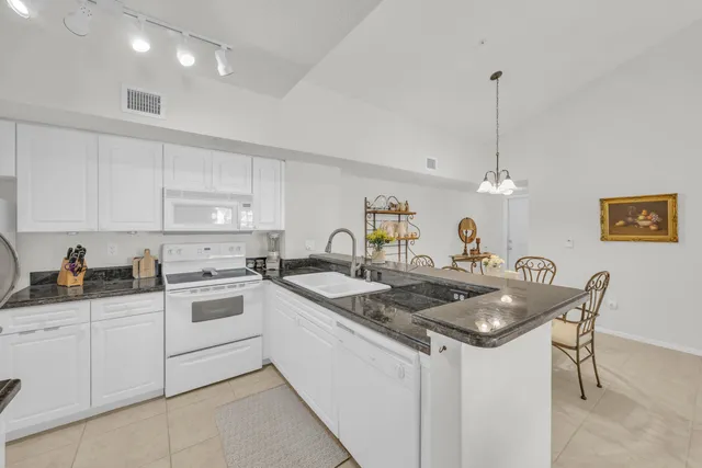 a kitchen with granite countertop a sink a stove a dining table and chairs