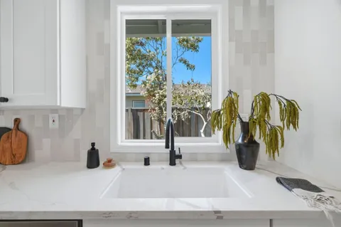 a white vase with flowers and white window