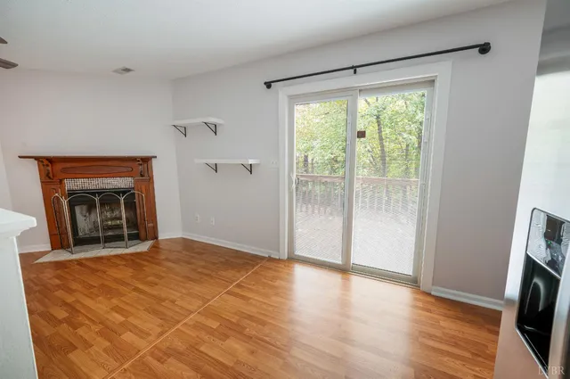 a view of an empty room with a window and a kitchen
