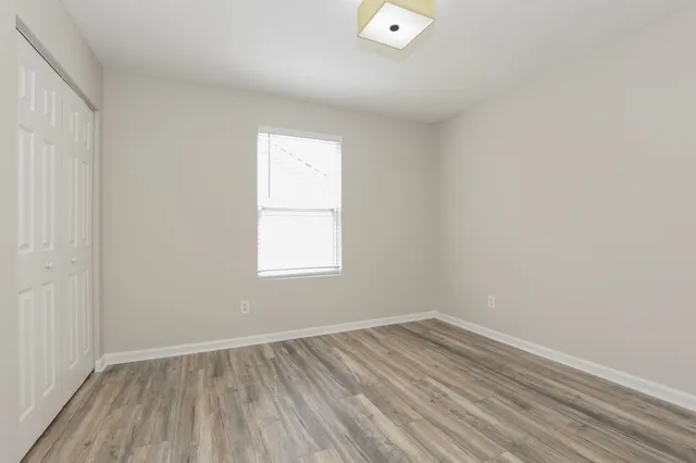 an empty room with wooden floor and windows