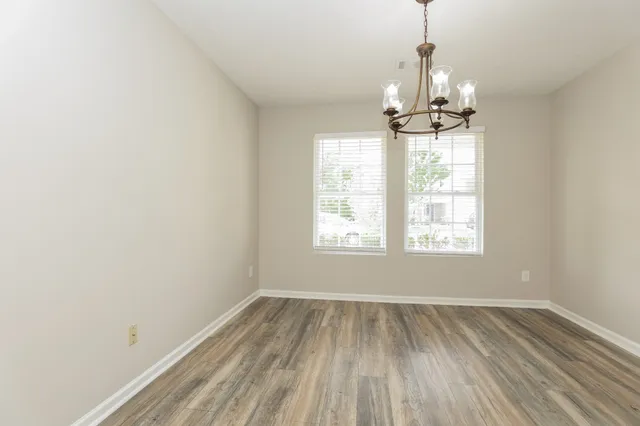 a view of empty room with wooden floor fan and window