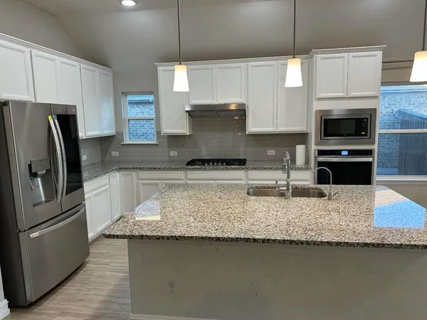 a metallic refrigerator freezer sitting in a kitchen