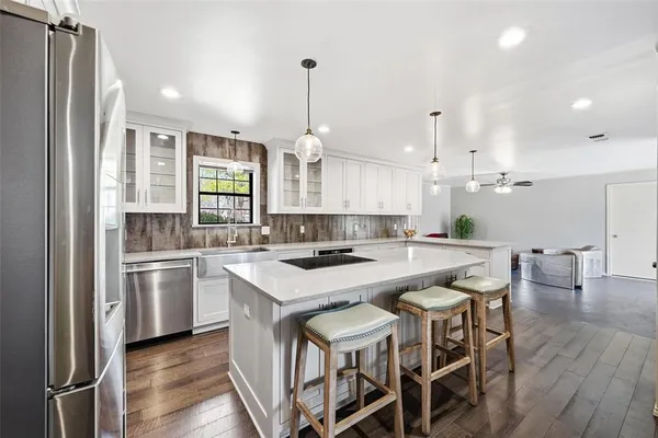 a kitchen with a dining table chairs wooden floor cabinets and appliances