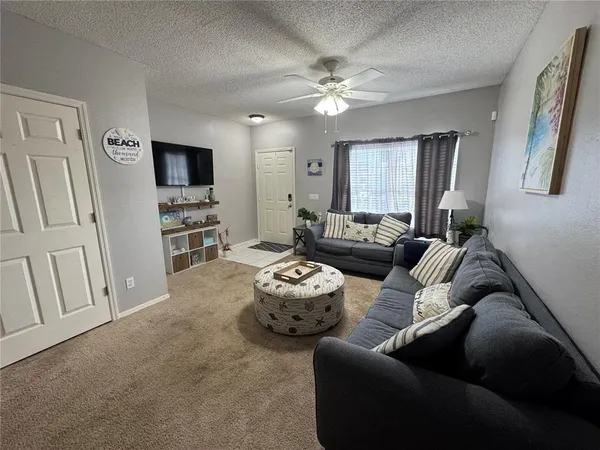 a living room with furniture a flat screen tv and kitchen view