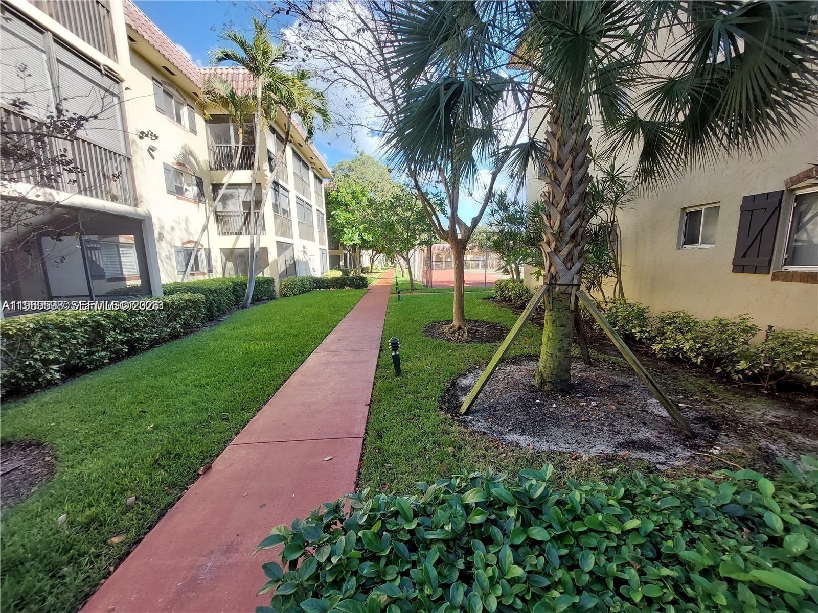 253 South Cypress Road, Unit 214 Pompano Beach, FL 33060 - Photo 17 of 25 a front view of a house with a yard and palm trees