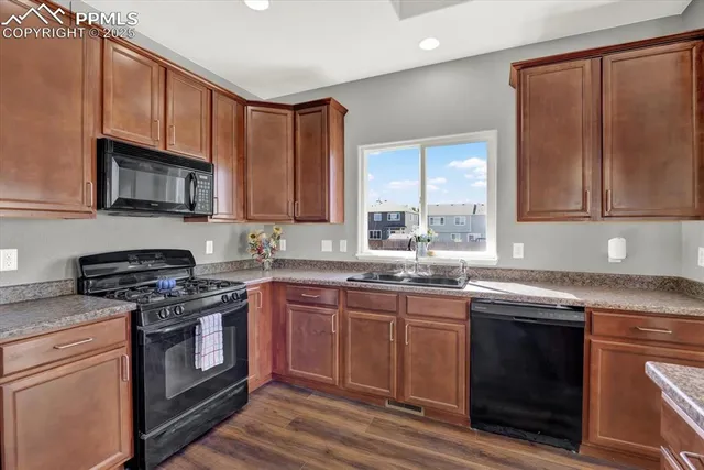 a kitchen with stainless steel appliances granite countertop wooden cabinets stove top oven and sink